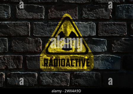 Radioaktives Zeichen an dunkler Ziegelwand. Gefahrensymbol Stockfoto