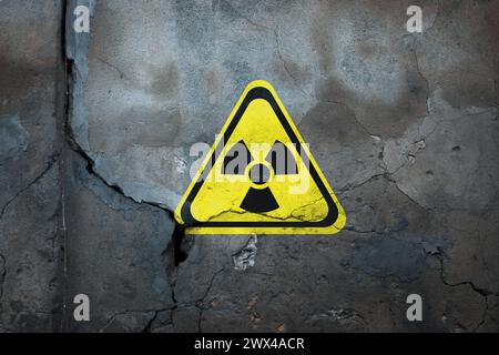 Radioaktives Zeichen an der alten, rissigen Wand. Gefahrensymbol Stockfoto