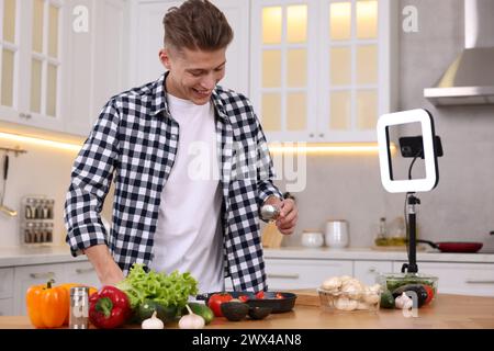 Lächelnder Food-Blogger kocht während der Videoaufnahme in der Küche Stockfoto