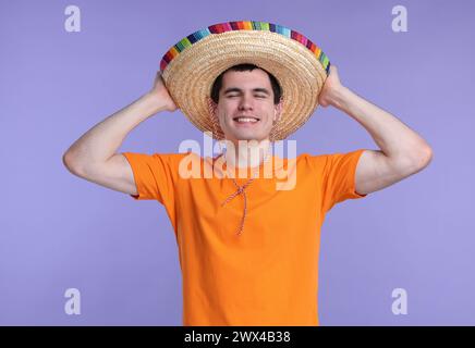 Junger Mann mit mexikanischem Sombrero-Hut auf violettem Hintergrund Stockfoto