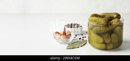 Leckere eingelegte Gurken und Gewürze auf hellem Hintergrund mit Platz für Text Stockfoto