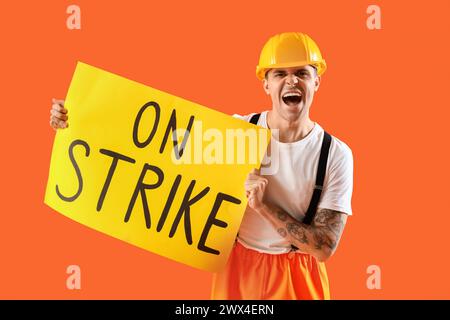 Protest gegen die Feuerwehr mit Plakat mit STREIKTEXT vor orangem Hintergrund Stockfoto