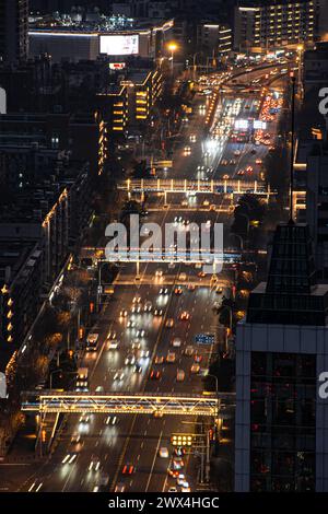 Die Kreuzung während der abendlichen Hauptverkehrszeit ist mit Fahrzeugen gefüllt. Über der Kreuzung befindet sich eine Fußgängerüberführung. Stockfoto