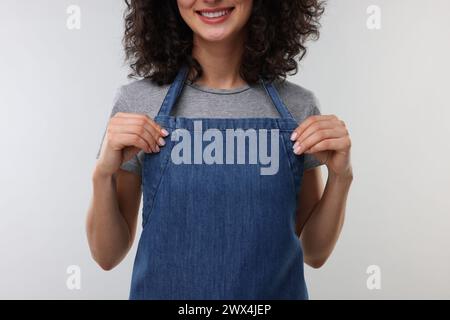 Frau mit Küchenschürze auf hellgrauem Hintergrund, Nahaufnahme. Modell für Design Stockfoto