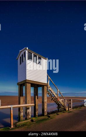 Ein Blick in der Nacht bei Mondlicht mit klarem Himmel und den Nordlichtern der Schutzhütte auf dem Damm auf Lindisfarne in Northumberland Stockfoto