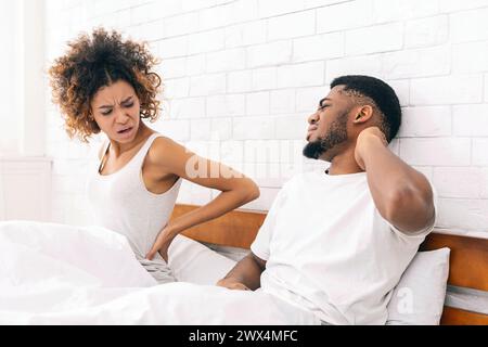 afroamerikanisches Ehepaar mit Rücken- und Nackenschmerzen im Bett Stockfoto