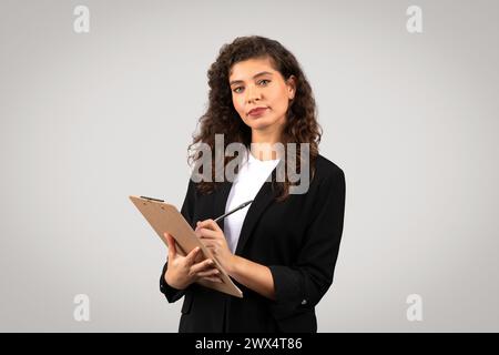 Geschäftsfrau mit Klemmbrett, die nachdenklich aussieht Stockfoto