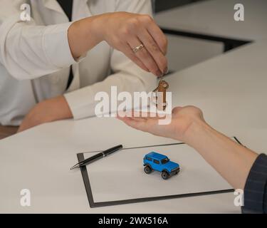 Autokauf-Angebot. Verkäufer übergibt Schlüssel an weibliche Kunden. Stockfoto