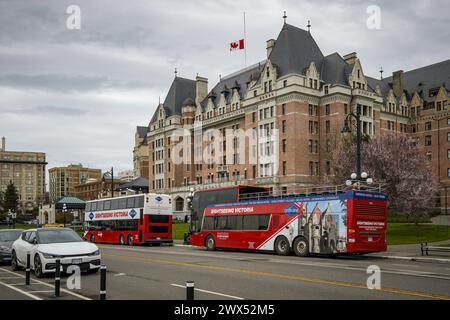 Foto von leuchtend roten Sightseeing-Bussen, die vor dem historischen Wahrzeichen des Hotels The Empress im Inner Harbor im Stadtteil der Innenstadt geparkt sind. Stockfoto