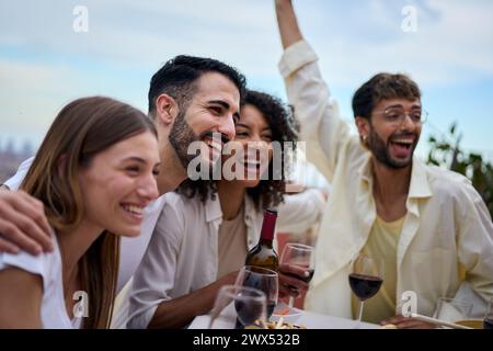 Eine Gruppe von Leuten sitzt an einem Tisch mit Weingläsern und einer Flasche Wein Stockfoto