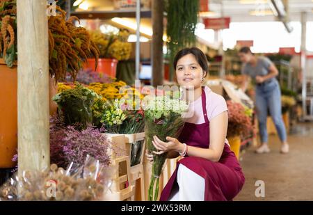 Porträt einer positiven Blumenmarktverkäuferin mit Gänseblümchen für Käufer Stockfoto
