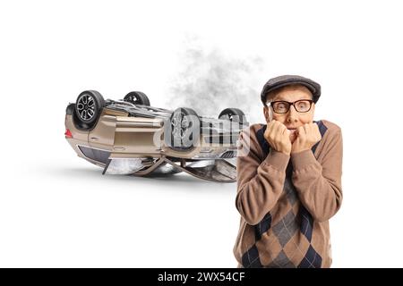 Ein verängstigter älterer Mann, der ein abgestürztes Auto auf blauem Hintergrund sieht Stockfoto