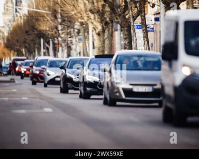 Eine lange Reihe von Autos zieht sich entlang einer belebten Straße, was zu Staus und Verzögerungen im städtischen Verkehrsfluss führt. Stockfoto