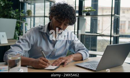 Fokussierter Geschäftsmann Geschäftsmann Buchhalter Büroangestellter schreibt Ideen in Notizbuchpapiere arabischer indischer Student schreibt Notizen Dateninformationen e Stockfoto