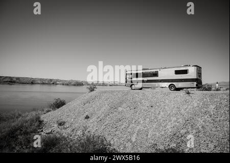 Ein großes Wohnmobil im Busstil, das am Ufer des Lake Havasu geparkt wird. Lake Havasu City, USA. Schwarzweißbild. Stockfoto