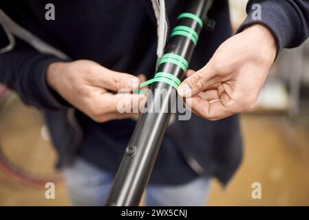 Unbekannte Person, die einen Fahrradrahmen mit Abdeckband für eine individuelle Bemalung in seiner Fahrradwerkstatt vorbereitet, ein handgefertigter kreativer Prozess. Stockfoto