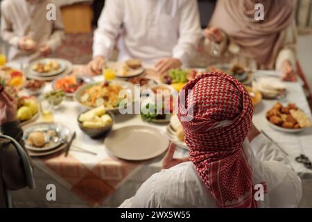 Selektive Fokusaufnahme eines nicht erkennbaren muslimischen Mannes, der Keffiyeh trägt und mit seiner Familie ein festliches Abendessen feiert, Kopierraum Stockfoto