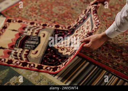 Hände an unerkennbaren muslimischen Mann, der Gebetsteppich auf den Boden im Wohnzimmer zu Hause legt, Kopierraum Stockfoto