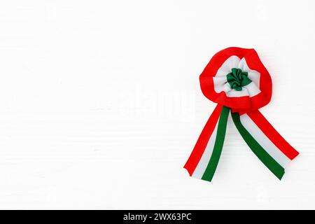 Kakade isoliert auf weißem hölzernem Hintergrund. Dreifarbiges Rosette-Symbol des ungarischen Nationalfeiertags 15. märz. Stockfoto