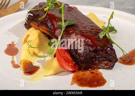 Rindfleisch auf dem Knochen mit Kartoffelpüree, garniert mit roter Sauce und Kirschtomaten. Kopierbereich Stockfoto
