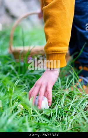 Die Kinderhand nimmt ein verstecktes Osterei auf Stockfoto