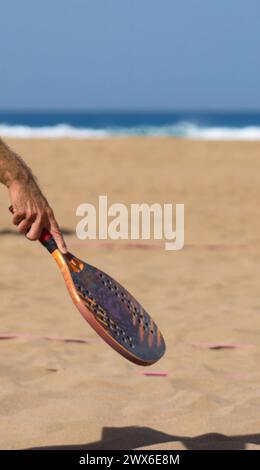 Männerhände mit Tennisschläger am Strand mit Sand und Meer Stockfoto