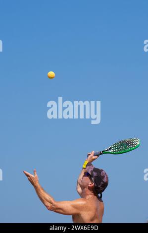 Ein Mann, der Strandtennis serviert Stockfoto