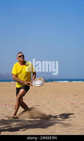 Senior Mann mit aktivem Lebensstil, der im Urlaub Strandtennis spielt Stockfoto