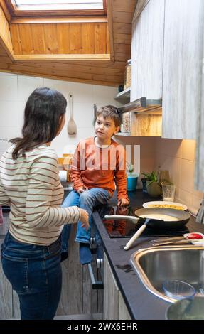 Junge kocht Pfannkuchen mit seiner Mutter zu Hause Stockfoto