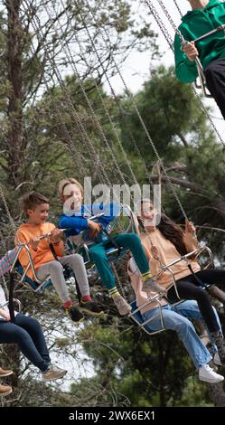 Familie mit einer Mutter und zwei Kindern, die auf einer Flugschaukel in einem Vergnügungspark fahren Stockfoto