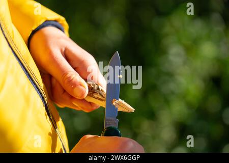 Junge, der einen Stock mit einem Rasierer schält Stockfoto