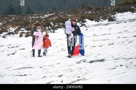 Harvey und Gemma Campbell mit den Kindern Jack, Arabella und Primrose Schlitten in den schneebedeckten Bedingungen auf Dartmoor. In Teilen Südwestenglands und Wales ist Schnee gefallen. Laut Wettervorhersage bewegt sich ein Gebiet mit Regen, Schneeregen und Bergschnee nach Norden durch Großbritannien, während sich Urlauber auf Osterausflüge vorbereiten. Bilddatum: Donnerstag, 28. März 2024. Stockfoto