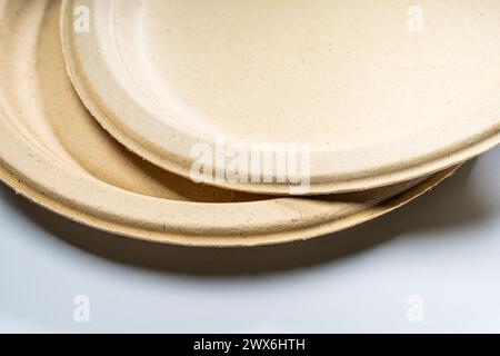 Einweg-Papierteller aus pflanzlichen Rohstoffen in beiger Farbe liegen auf dem Tisch. Stockfoto