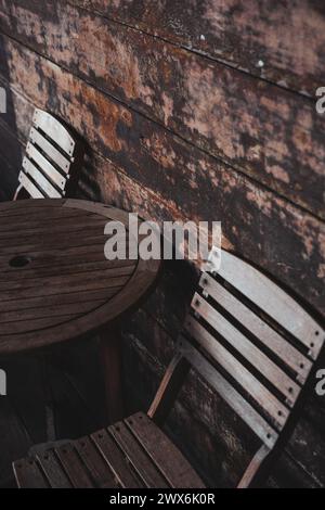Die zwei Stühle und ein Holztisch mit zwei leeren Stühlen sind in einer Reihe angeordnet. Stockfoto