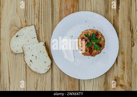 Reis mit Huhn, Gemüse und Kräutern auf einem Teller mit horizontaler Draufsicht. Zwei Scheiben Weißbrot mit Kleie Stockfoto