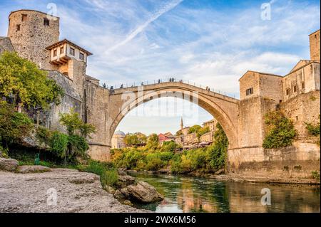 Historische Mostar Bridge, auch bekannt als Stari Most oder Old Bridge in Mostar, Bosnien und Herzegowina. Skyline von Mostar Häusern und Minaretten, bei Sonnenuntergang Stockfoto