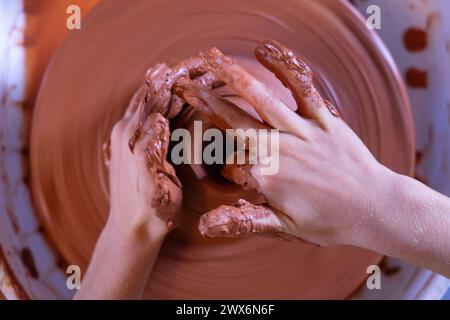 Kinderhände, die eine Schüssel auf einem Töpferrad Formen Stockfoto