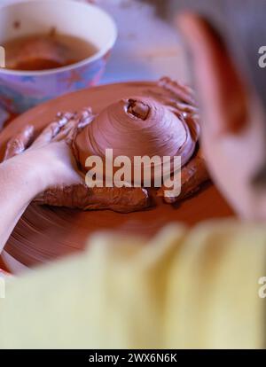 Junge, der ein Stück Ton auf einem Töpferrad in einer Töpferwerkstatt formt Stockfoto