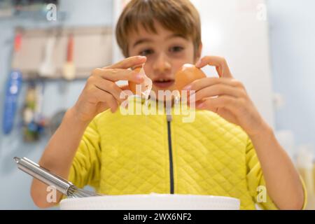 Ein Kind knackt ein Ei, um hausgemachten Teig zu machen Stockfoto