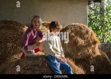 Zwei Kinder sitzen im Heu auf einer Farm Stockfoto