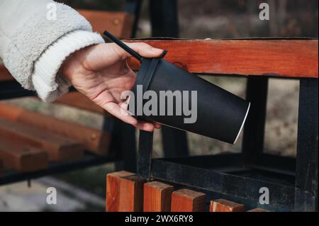 Frau Hand wirft einen recycelbaren Karton Kaffee in einen Mülleimer in einem Park Stockfoto