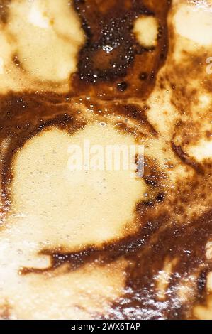 Ein Kaffee, der zu einem Kunstwerk wird, mit abstrakten Mustern im Schaum, die mit Kontrasten von Farbe und Textur spielen. Stockfoto