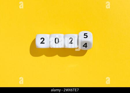 Neujahr von 2024 bis 2025 Konzept. Text auf Cube-Blöcken isoliert auf gelbem Hintergrund Stockfoto