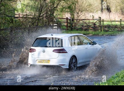 Eton, Windsor, Berkshire, Großbritannien. März 2024. Fahrzeuge spritzen heute nach starkem nächtlichem Regen auf der Landstraße in Eton, Windsor, Berkshire durch Hochwasser. Da der Sonnenschein schnell zu starkem Regen überging, wird Storm Nelson das Vereinigte Königreich über das Ostermontag-Wochenende in die Höhe treiben. Quelle: Maureen McLean/Alamy Live News Stockfoto