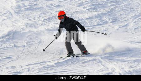 Nahaufnahme eines männlichen Skifahrers, der einen Bergsteiger mit Helm und Schutzbrille fährt. Stockfoto