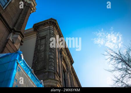 Erkunden Sie den Charme und das architektonische Erbe Amsterdams durch seine lebhaften Straßen, wo ikonische Gebäude ein malerisches Stadtbild prägen. Stockfoto