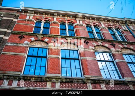 Erkunden Sie den Charme und das architektonische Erbe Amsterdams durch seine lebhaften Straßen, wo ikonische Gebäude ein malerisches Stadtbild prägen. Stockfoto