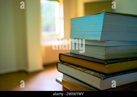 Ein mit Büchern geschmückter Schreibtisch schafft einen organisierten und optisch ansprechenden Raum, der perfekt zum Studium und zur intellektuellen Erkundung geeignet ist. Stockfoto