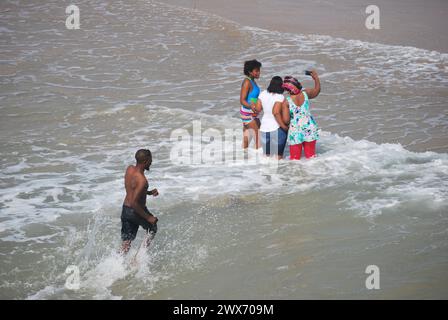 Junge Leute am Meer, die scherzen und Fotos machen Stockfoto