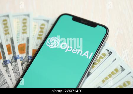 KIEW, UKRAINE - 17. MÄRZ 2024 OpenAI-Logo auf dem iPhone-Display mit vielen hundert Dollar-Scheinen. Engine für künstliche Intelligenz Stockfoto